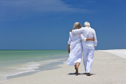 senior couple walking on beach together holding hands