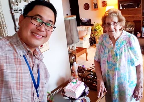 young man surprising old lady with birthday cake