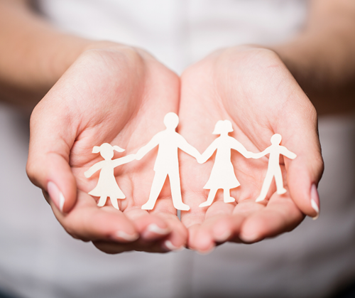 hands holding a paper cut out of four children